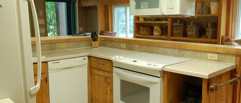 A kitchen with wooden cabinets, a microwave, a stove, and a dishwasher.