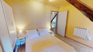 Une chambre à coucher avec un lit, des tables de chevet, une lampe et un radiateur.