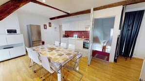 Une cuisine moderne avec des meubles blancs, un plan de travail rouge et un coin repas comprenant une table et des chaises.