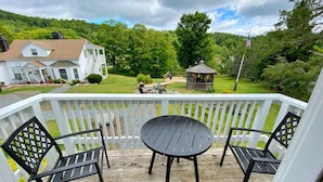 A wooden deck with a table and chairs, overlooking a lush green landscape and a gazebo. - Deluxe King, Living Room w/sofa bed & fireplace (Dover)