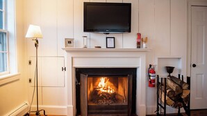 A fireplace with a TV above it, a lamp to the left, and a fire burning. - Deluxe King, Living Room w/sofa bed & fireplace (Dover)