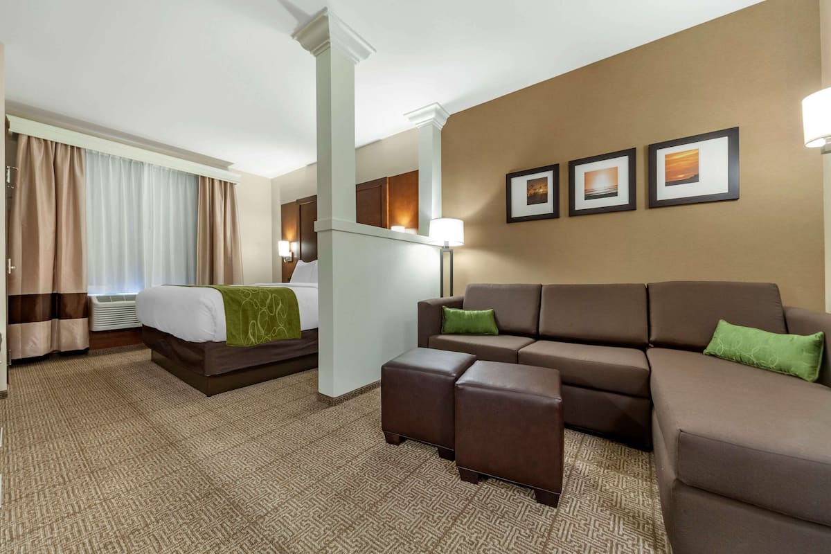 Ett hotellrum med en säng, en soffa, ett soffbord och en vägg med inramade tavlor.