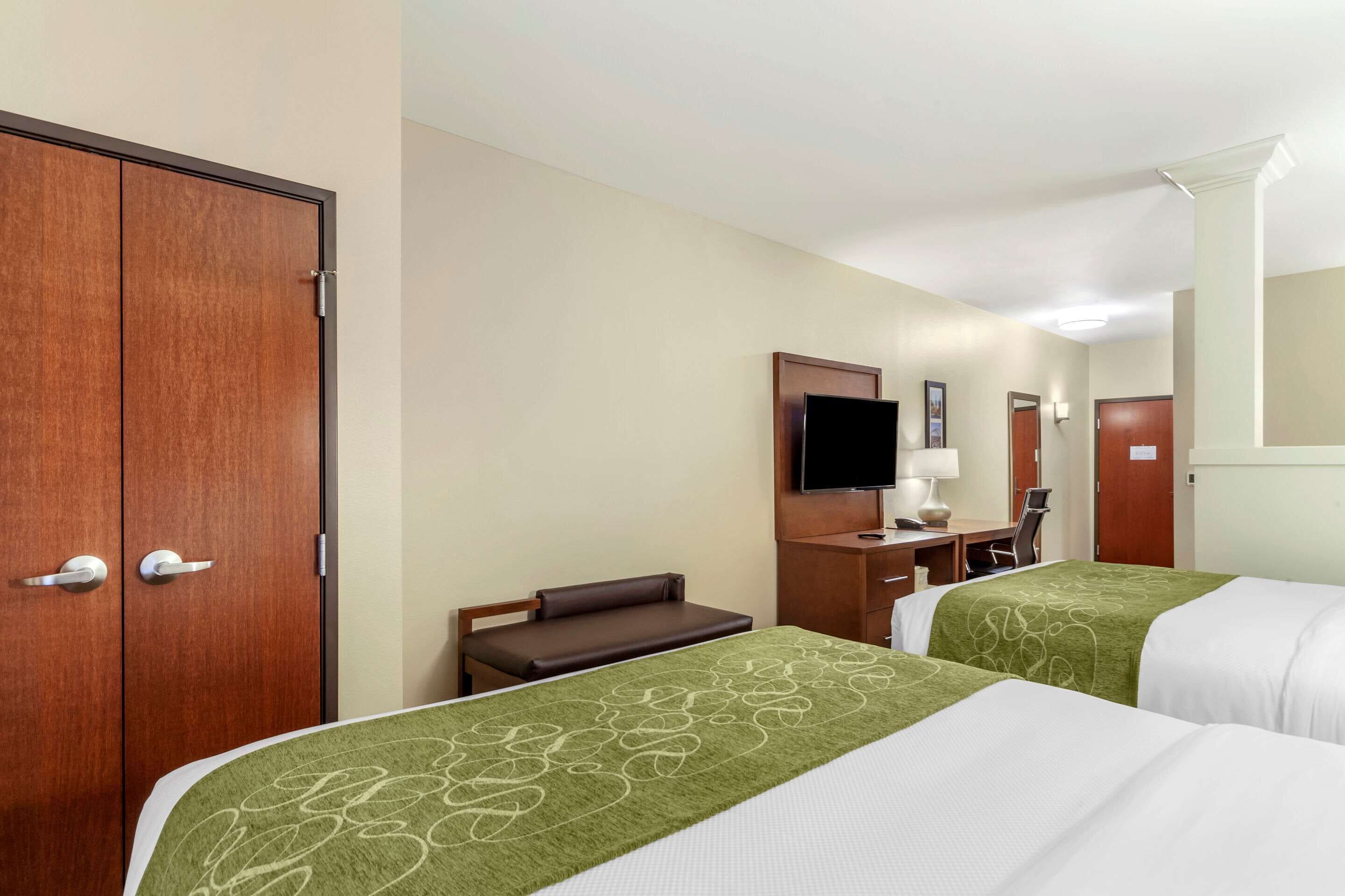 Habitació d'hotel amb dos llits, un escriptori, una cadira, un televisor i un armari.