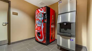 Un distributeur automatique orné du logo Coca-Cola, un point d’eau et un panneau indiquant les consignes d’entretien affiché sur le mur.