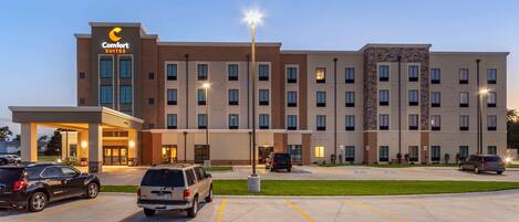 A Comfort Suites hotel with a parking lot, multiple entry points, and a well-lit exterior.