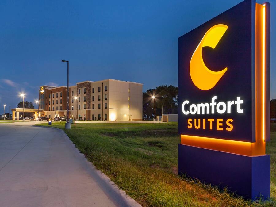 A Comfort Suites hotel sign with a modern building in the background.