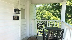 A covered porch with a table and chairs, a lantern, and a framed picture on the wall. - Deluxe King, Living Room w/sofa bed, bunk bed & fireplace (Dover)