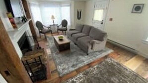 A living room with a sofa, chairs, a coffee table, and a fireplace. - Deluxe King, Living Room w/sofa bed, bunk bed & fireplace (Dover)