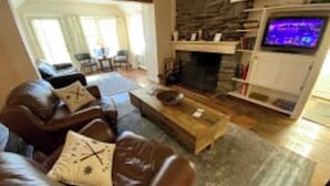 Ein Wohnzimmer mit Kamin aus Stein, einer Ledersofa und einem Fernseher.