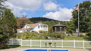 Una propiedad residencial con piscina, cerca de piquetes blancos y un pabellón.