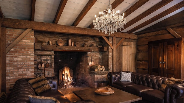 Una sala de estar acogedora con chimenea, sofás de cuero, una mesa de centro de madera y un candelabro.