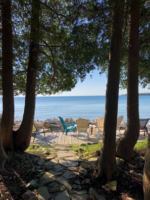 Eine Holzterrasse mit Stühlen und Tisch, mit Blick auf ein ruhiges Meer.