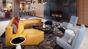 Un salon moderne avec un grand canapé, une table basse et une cheminée. Au fond, on aperçoit un coin repas avec une table et des chaises.