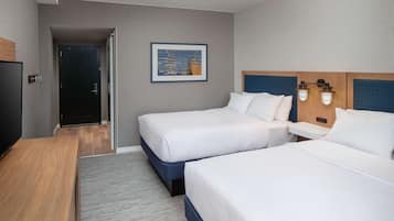 Une chambre d’hôtel avec deux lits, un bureau, une télévision et un tableau au mur.