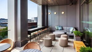 Un espace extérieur moderne, aménagé avec des tables rondes, des sièges rembourrés et des plantes en pot.