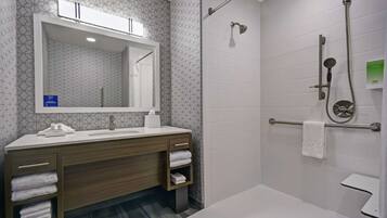 Un baño moderno con ducha, un lavabo con espejo y un perchero para toallas.