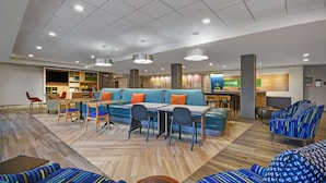 A modern hotel lobby with a central seating area, a bar, and a reception desk. - Home2 Suites by Hilton Springdale Cincinnati (Cincinnati)