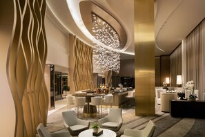 A modern hotel lobby with a bar area, seating arrangements, and decorative lighting. - Hilton Miami Aventura (Aventura)