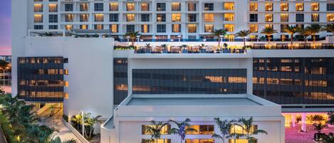 Un hôtel Hilton moderne, doté de plusieurs étages, d’un hall d’entrée bien éclairé et d’une cour aménagée avec des palmiers.