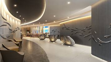 Eine moderne Lobby mit gebogenen Sitzgelegenheiten, einem Empfangsbereich und einer großen Wand mit abstrakter Metallkunst.