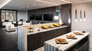 Una cocina moderna con encimera de mármol, electrodomésticos integrados y una zona de estar con sofá y sillones.