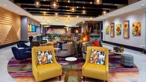 A modern lobby with two yellow armchairs, a central coffee table, and a colorful carpet.