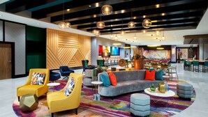 A modern lobby with a central seating area, a bar, and a colorful carpet.