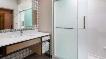 Un baño moderno con un espejo grande, un lavabo, cabina de ducha de vidrio y un perchero para toallas.