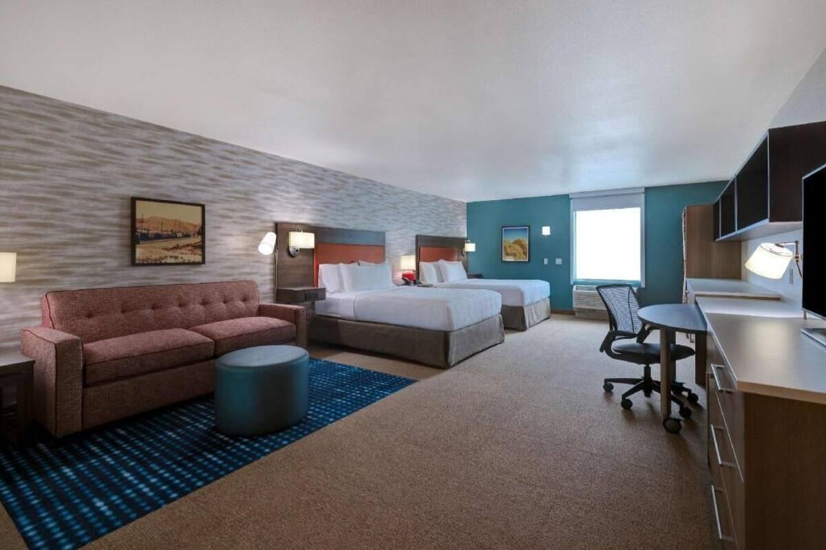 A hotel room with a bed, a sofa, a desk, and a TV.