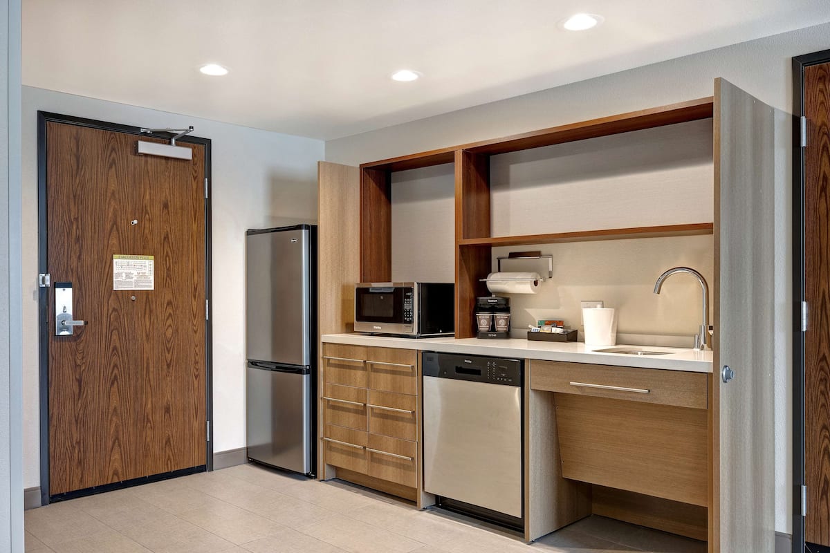 A modern kitchen with a built-in microwave, refrigerator, dishwasher, and wooden cabinetry.