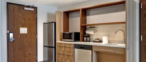 A modern kitchen with a built-in microwave, refrigerator, dishwasher, and wooden cabinetry.