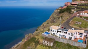 Um imóvel costeiro com uma casa moderna, piscina e vista para o mar.