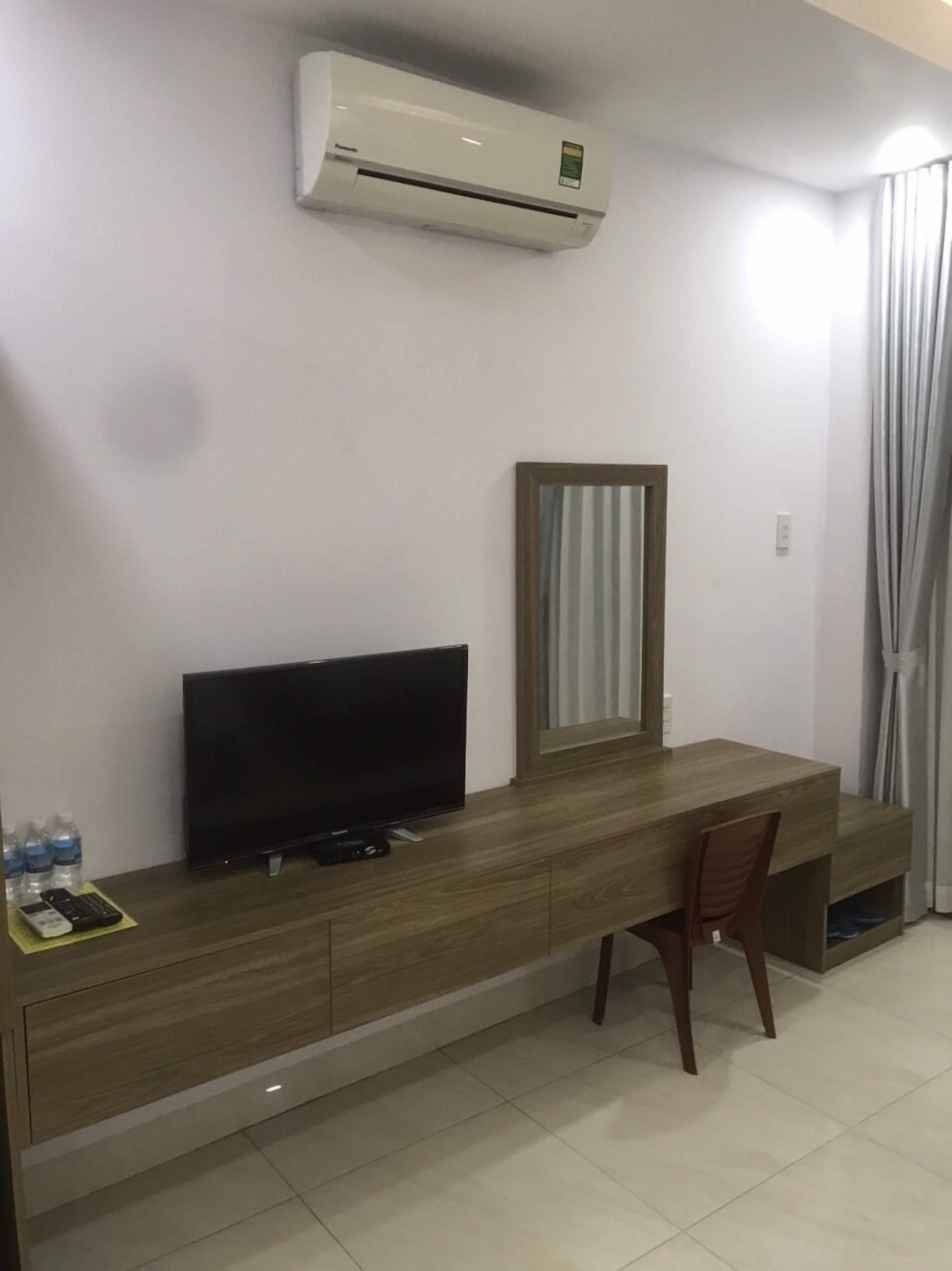 Une chambre d’hôtel équipée d’un bureau en bois, d’un téléviseur à écran plat, d’un miroir et d’un appareil de climatisation.