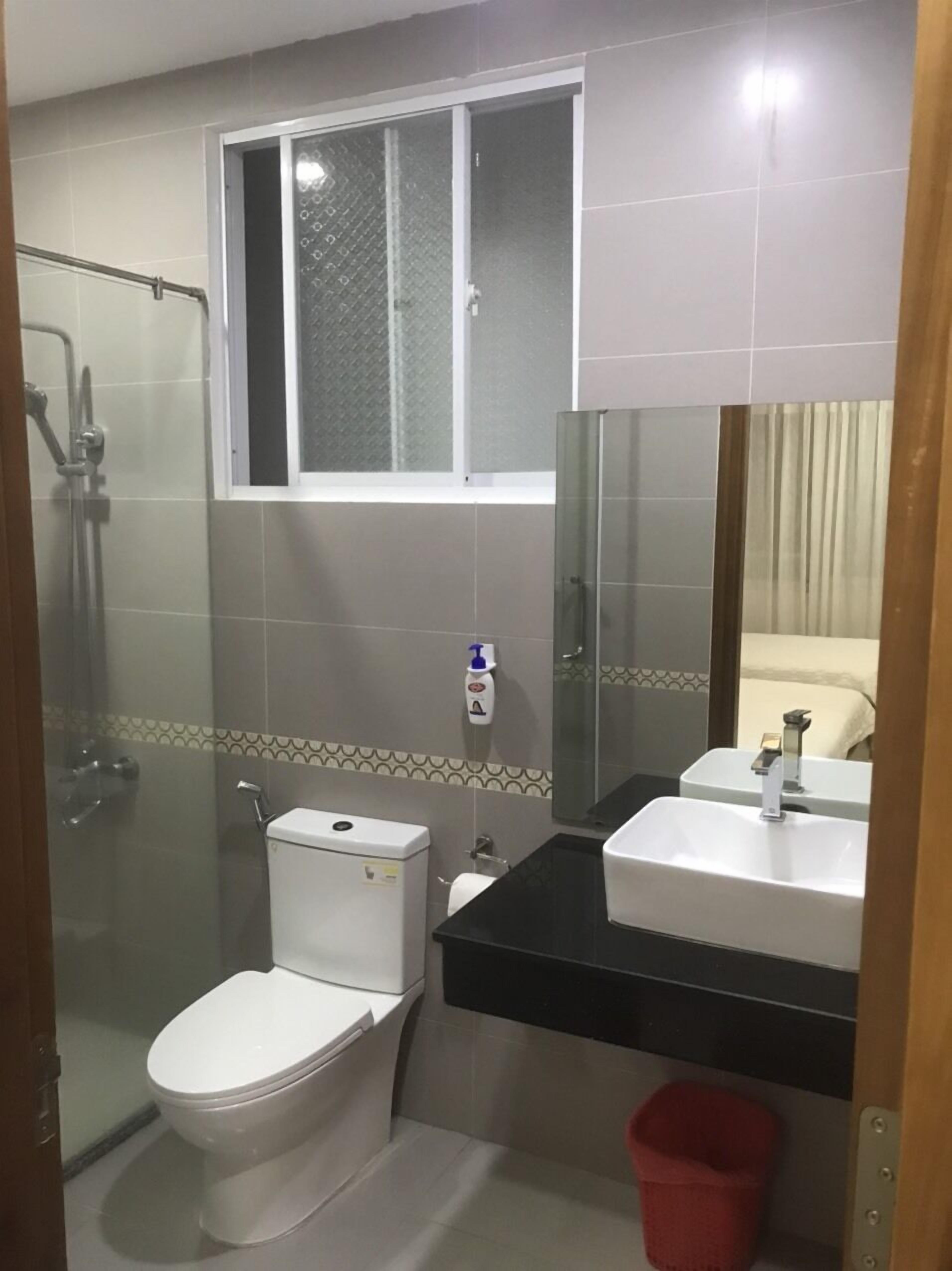 A bathroom with a toilet, a shower, a sink, and a window.