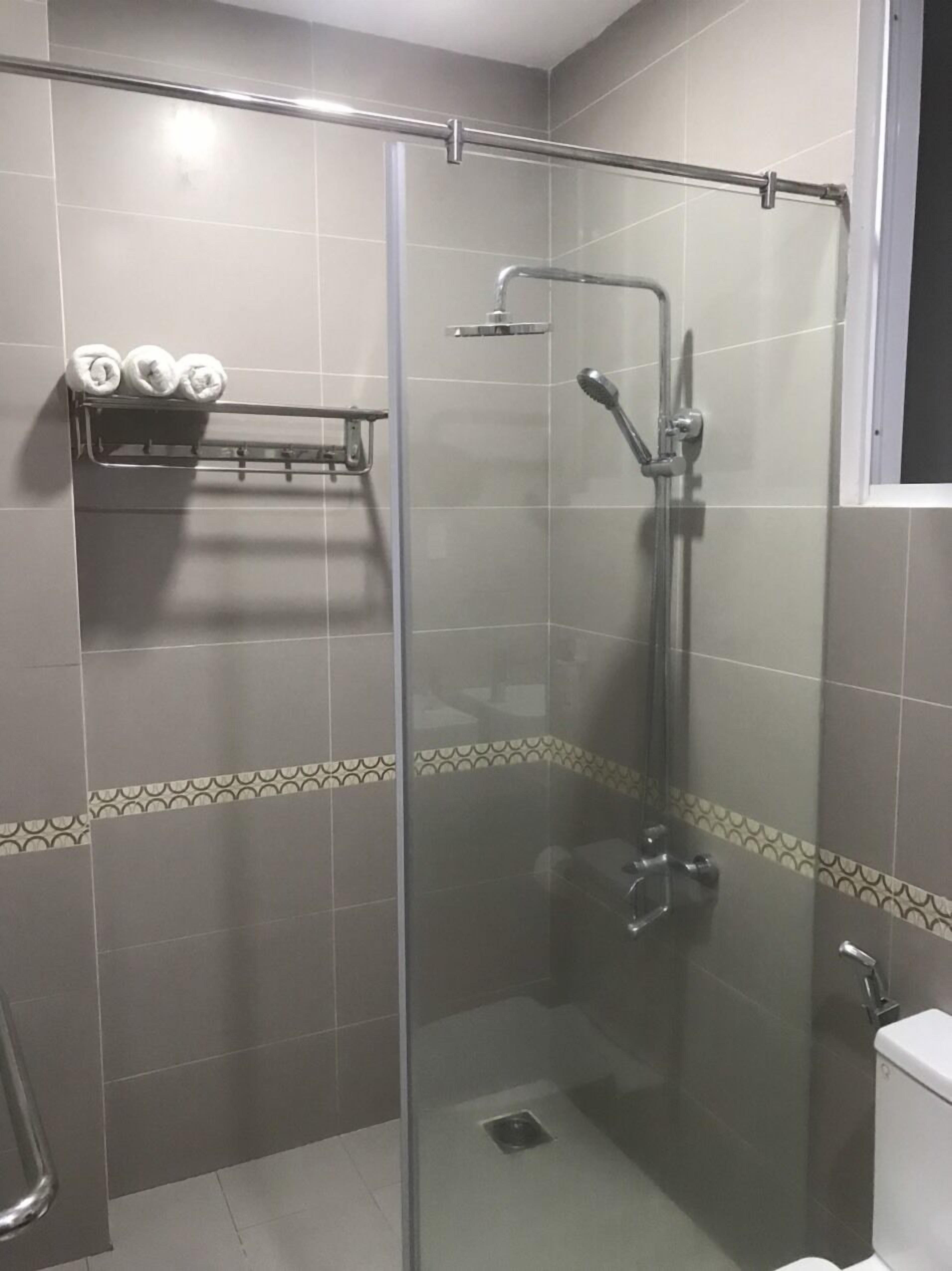 A glass-enclosed shower with a handheld showerhead and a handheld faucet.