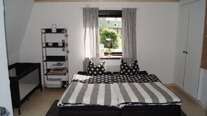A bedroom with a bed, a shelf with storage bins, and a window with curtains.