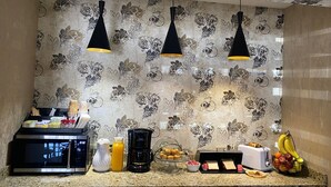 A kitchen counter with a microwave, coffee maker, toaster, and various breakfast items. - Casagrande Hotel (Monclova)