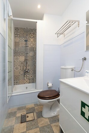 Bathroom features a shower area with a patterned tile design, a toilet, and a sink with a mirror.