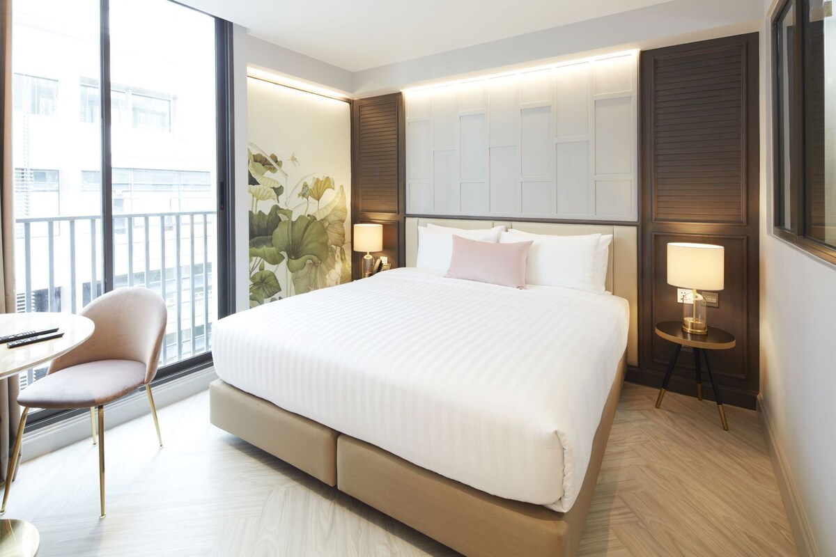 Une chambre d’hôtel moderne, dotée d’un grand lit, d’une chaise, d’un bureau et offrant une vue sur la ville.