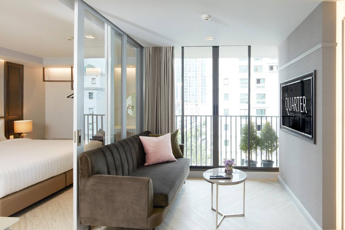 A modern hotel room with a bed, sofa, and a small coffee table.
