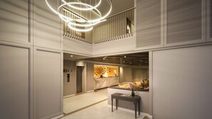 Eine moderne Hotelhalle mit einer zentralen Rezeption, einer Treppe und einer dekorativen Leuchte.