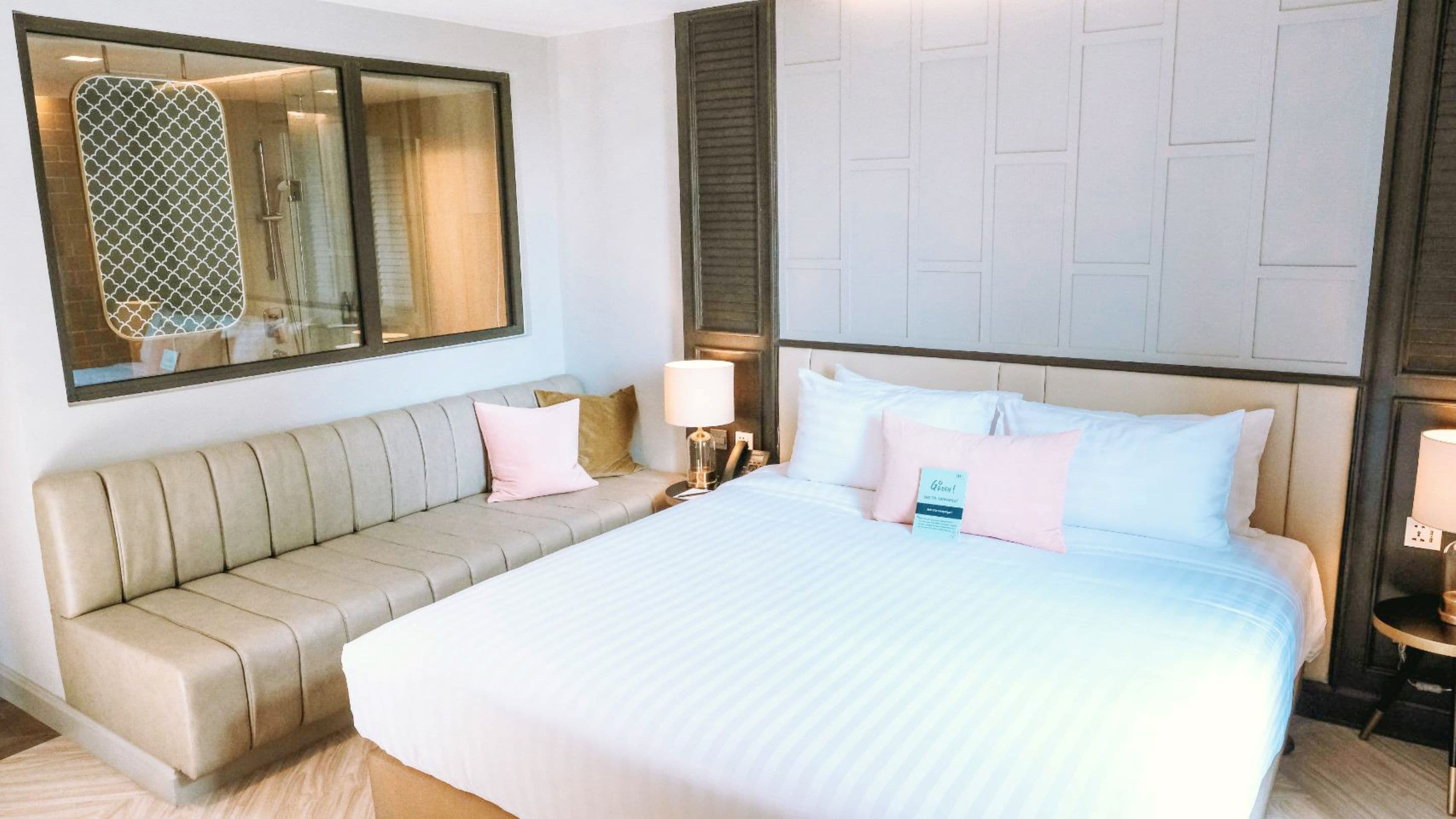 Una habitación de hotel con una cama grande, un sofá, un espejo y una ventana con persianas.