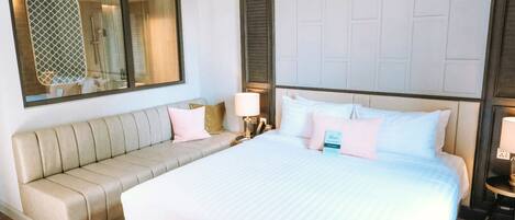 Una habitación de hotel con una cama grande, un sofá, un espejo y una ventana con persianas.