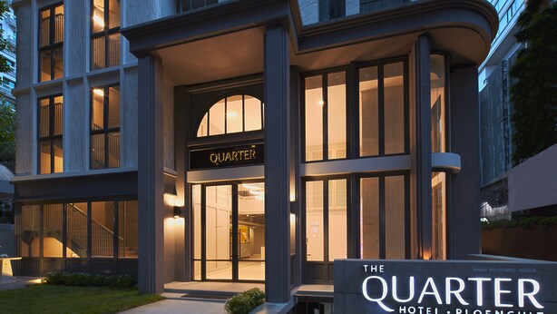 Ein moderner Hotel Eingang mit Glastüren und einem Schild mit dem Schriftzug 'The Quarter Hotel'.