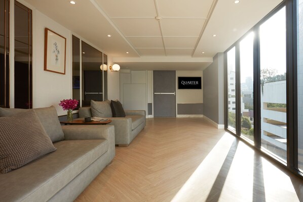 A modern living room with a sofa, a coffee table, and a vase of flowers. There is a sign that says "QUARTER" on the wall.