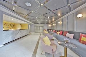 Un hall d’hôtel moderne comprenant un comptoir d’accueil, un espace salon et un mur décoratif.