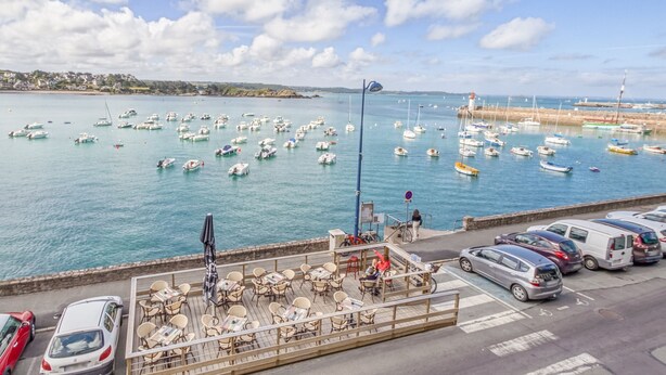 A marina with numerous boats docked, a café with outdoor seating, and a parking area with cars. - LE MATELOT 3* - Superbe appartement vue mer - Erquy (Erquy)