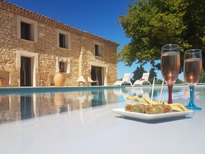 A stone building with a pool, lounge chairs, and a plate of olives and breadsticks. - Mas de Fugueyrolles Suite Luberon (Cavaillon)