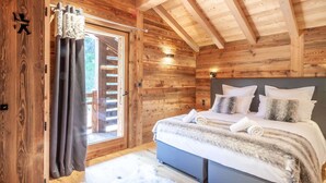 Une chambre dans une cabane en bois, avec un lit, des rideaux et une fenêtre.