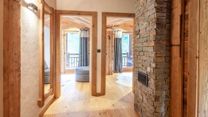 Un couloir doté d’un plancher en bois, d’un mur en pierre et de portes en bois donnant sur un balcon avec vue.